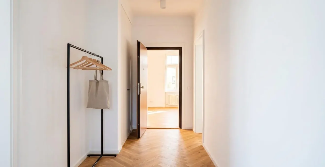 Vue grand angle d'une entrée d'appartement français moderne avec porte ouverte laissant entrer la lumière naturelle